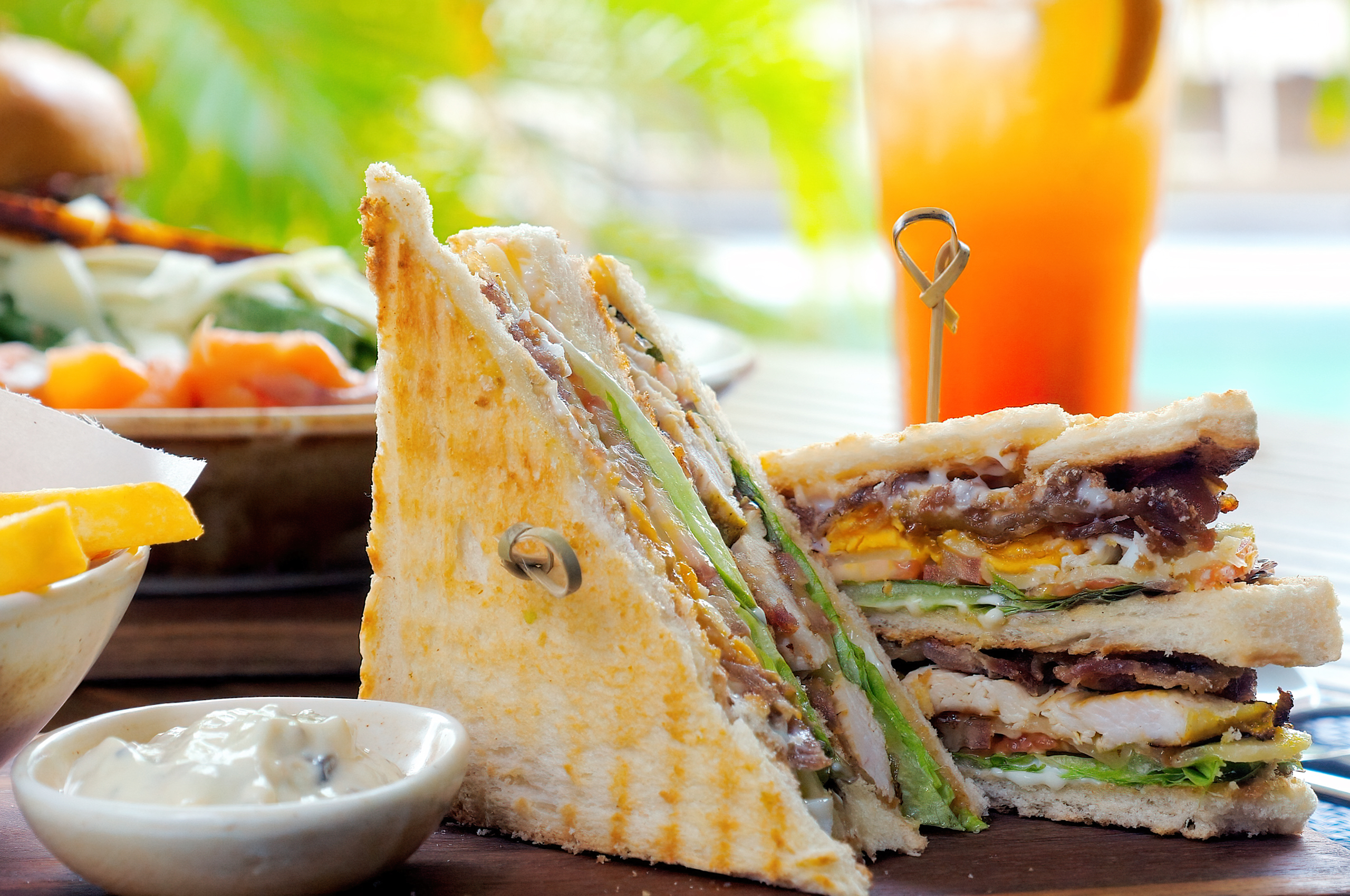 Club sandwich with dip and orange drink.
