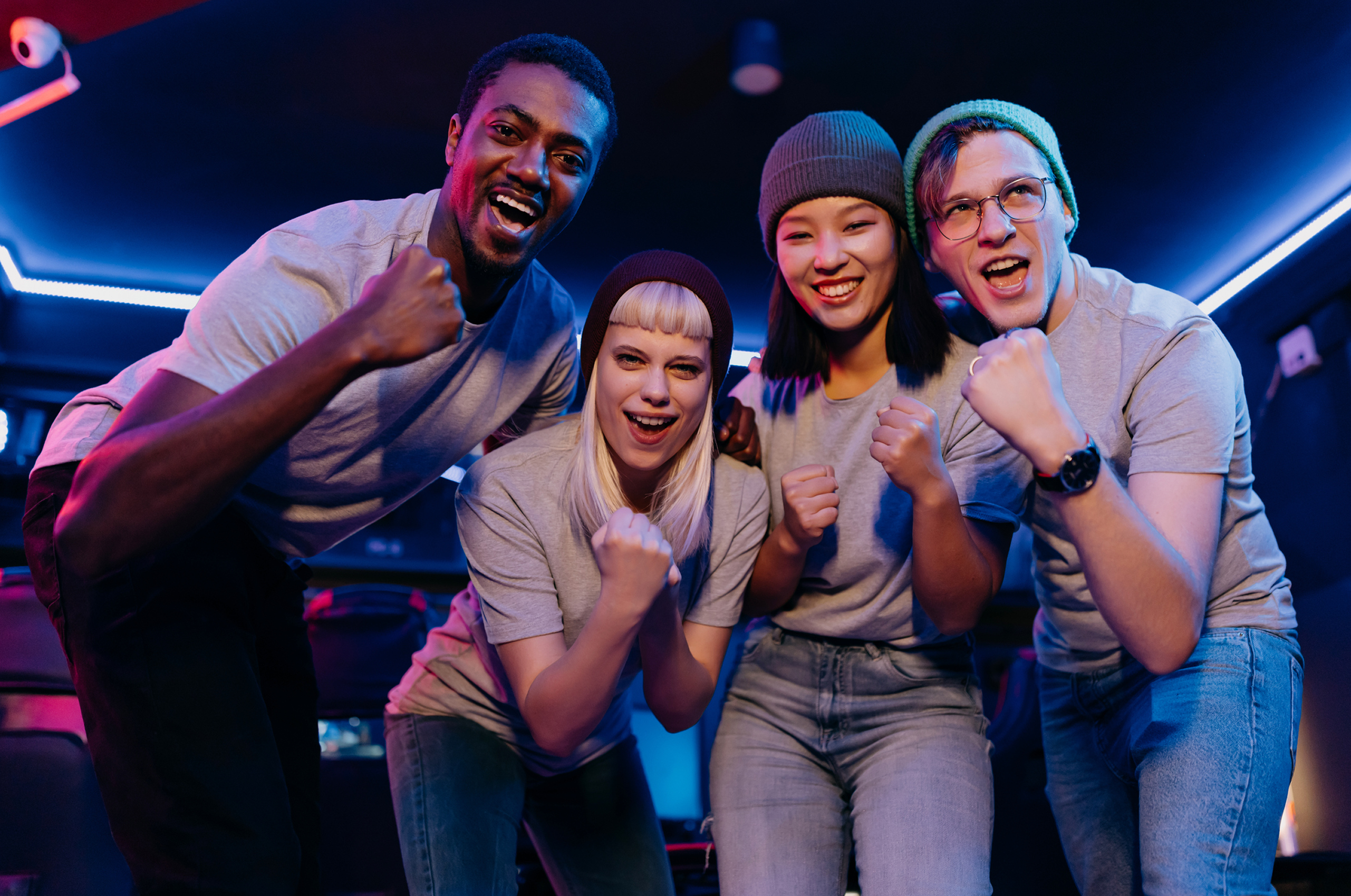 Group of friends cheering in neon lighting.
