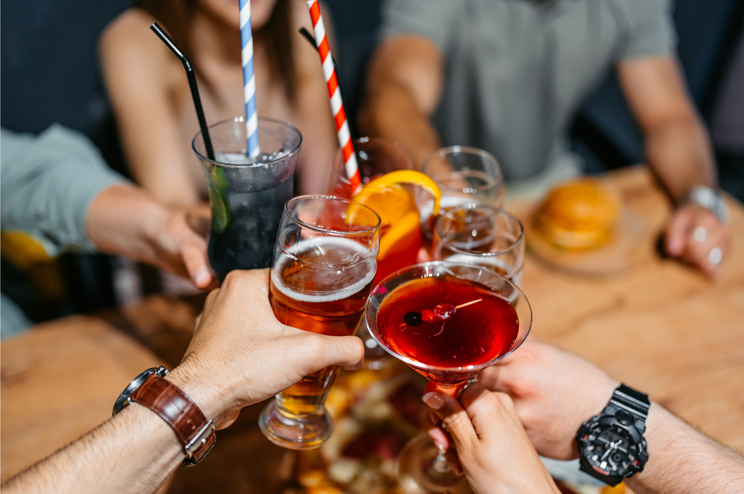 People toasting with various colorful drinks.
