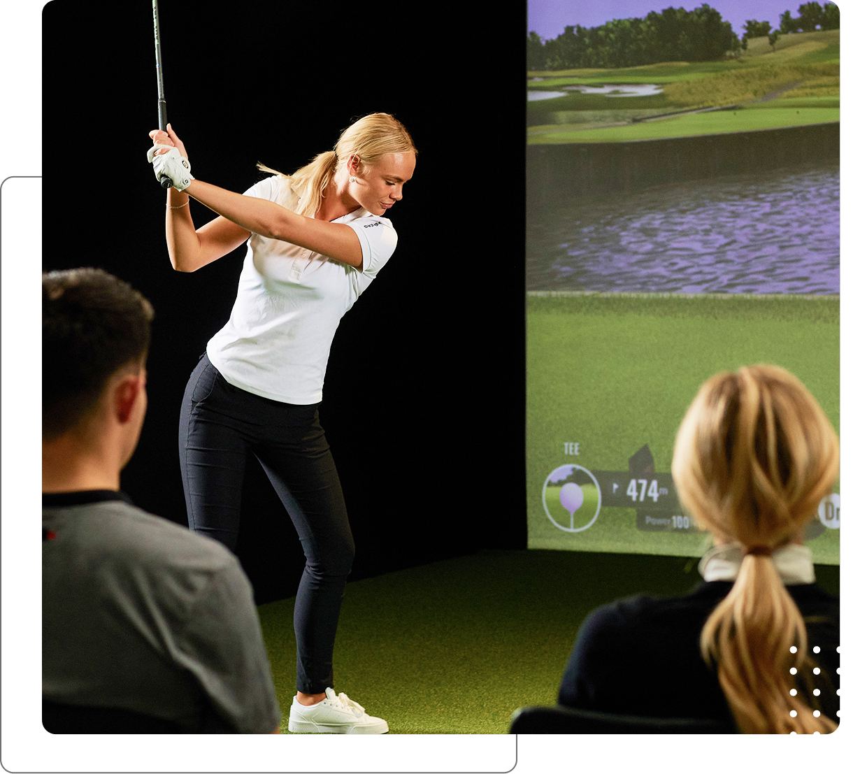 Woman playing indoor golf simulator game.